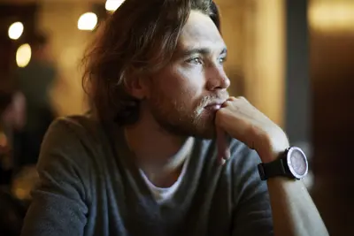 Ein Mann stützt mit seiner Hand sein Kinn und schaut in die Ferne