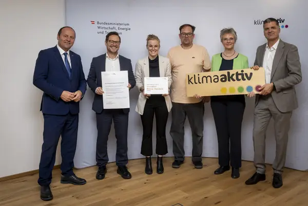 mehrere Personen mit Urkunde in der Hand schauen in die Kamera