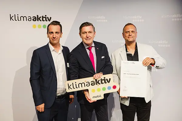 Menschen mit Urkunde und klimaaktiv Schild lächeln in die Kamera
