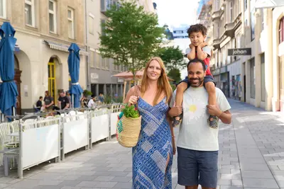 Familie mit Kleinkind zu Fuß unterwegs. Das Kind sitzt auf den Schultern des Vaters