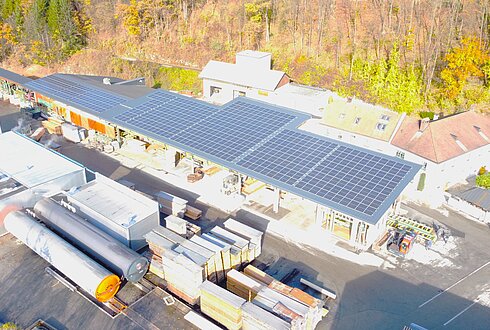 Luftaufnahme von Gebäuden des Holzverarbeitungsbetriebs mit Solarpaneelen auf den Dächern.