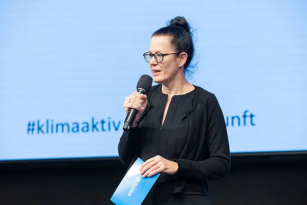 Frau auf einer Bühne spricht ins Mikro