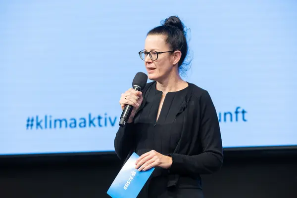 Frau auf einer Bühne spricht ins Mikro