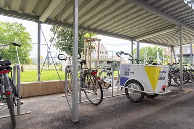 Große überdachte Radabstellanlage. Darunter parkt ein Transportrad.