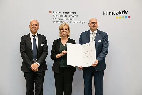 Auszeichnung von klimaaktiv Vorzeigebetrieb B&R Industrial Automation GmbH durch Klimaschutzministerin Leonore Gewessler (BMK). Im Bild: Robert Perperschlager (Global Operations Development Manager) (rechts), Franz Baischer (Health, Safety and Environment - Sustainability Specialist) (links) mit Klimaschutzministerin Leonore Gewessler (BMK) (mitte)