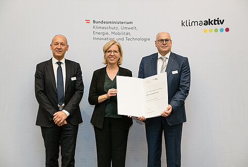 Auszeichnung von klimaaktiv Vorzeigebetrieb B&R Industrial Automation GmbH durch Klimaschutzministerin Leonore Gewessler (BMK). Im Bild: Robert Perperschlager (Global Operations Development Manager) (rechts), Franz Baischer (Health, Safety and Environment - Sustainability Specialist) (links) mit Klimaschutzministerin Leonore Gewessler (BMK) (mitte)