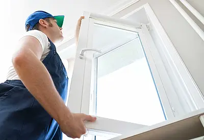 Mann im Overall installiert ein Fenster