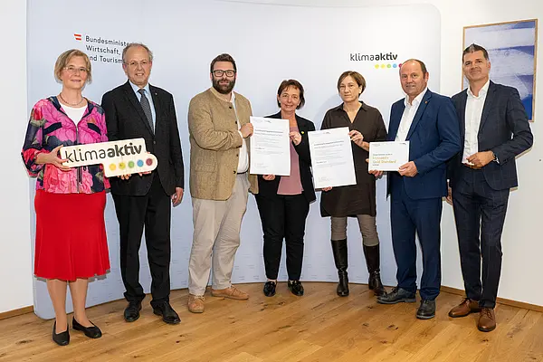 eine Gruppe von Menschen auf einer Bühne hält Urkunden in die Kamera