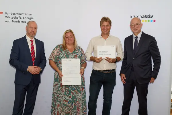 4 Personen mit Urkunde schauen in die Kamera