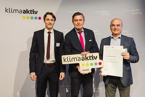 Menschen mit Urkunde und klimaaktiv Schild lächeln in die Kamera