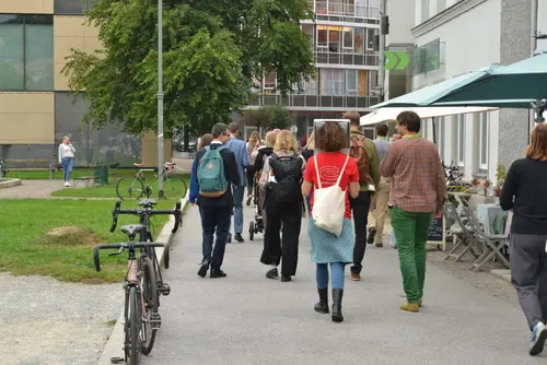 Viele gehene Personen zwischen Häusern und Grünfläche