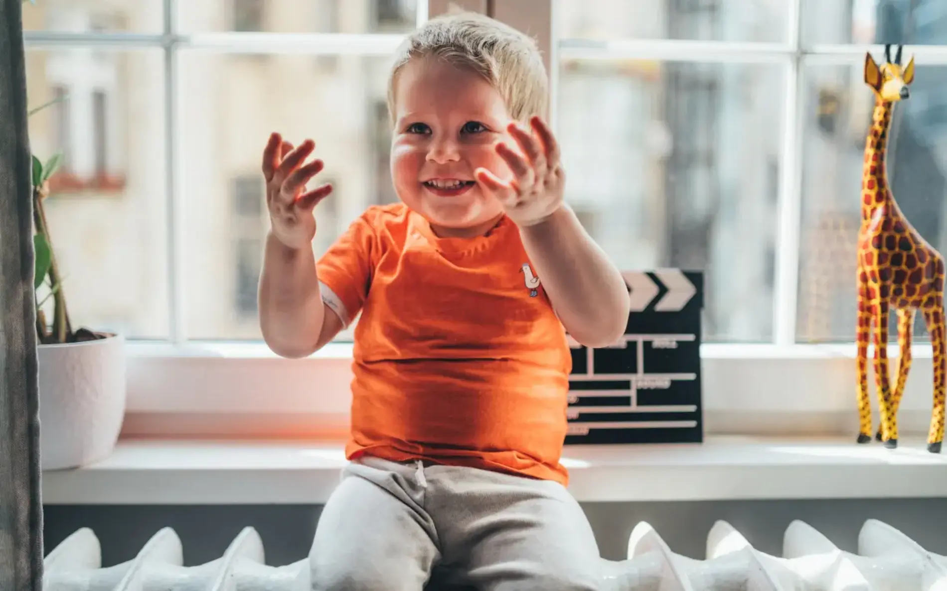 Kind sitzt auf einem Heizkörper