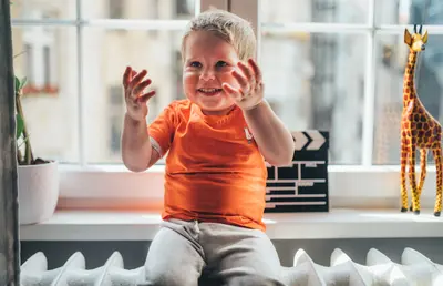 Kind sitzt auf einem Heizkörper