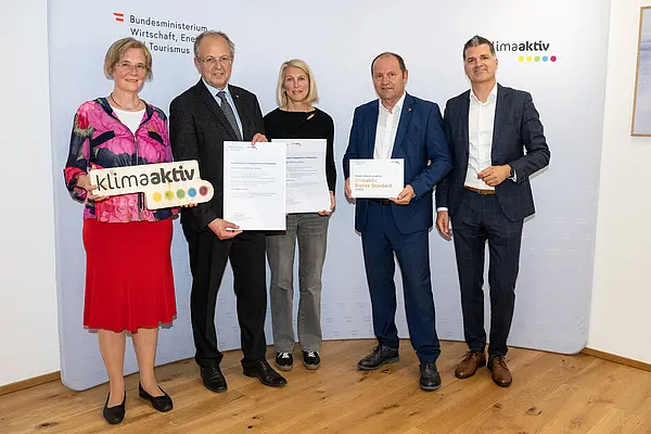 eine Gruppe von Menschen auf einer Bühne hält Urkunden in die Kamera