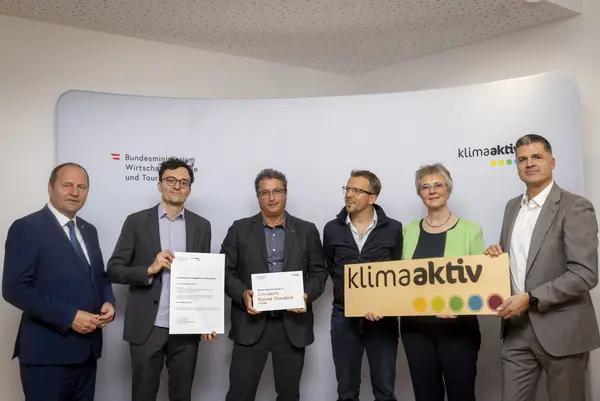 Menschen mit Urkunde schauen in eine Kamera