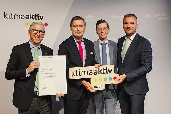 Menschen mit Urkunde und klimaaktiv Schild lächeln in die Kamera