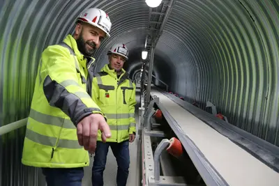 Förderbadanlage für Trockenmörtel, daneben stehen zwei Arbeiter mit Helm und Neonfarbener Warnjacke