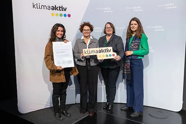 4 Personen mit Urkunde und klimaaktiv Schild schauen in die Kamera