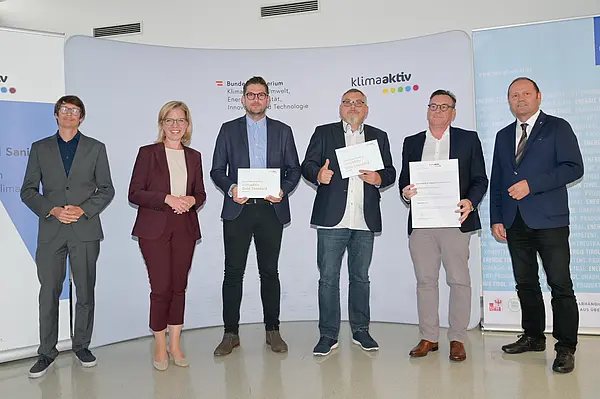 Im Bild: Klimaschutzministerin Leonore Gewessler, LHStv. Josef Geisler, DI Robert Taunmüller (Energie Tirol), Mag. DI Markus Pollo und DI Harald Konrad Malzer (NEUE HEIMAT TIROL, Gemeinnützige WohnungsGmbH), Robert Waldner (FIBY ZT GmbH)