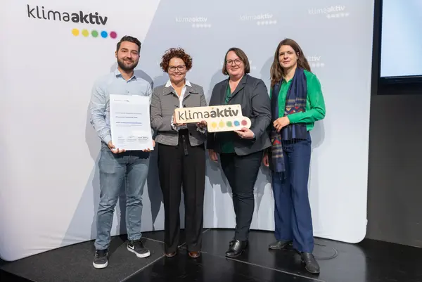 4 Personen mit Urkunde und klimaaktiv Schild schauen in die Kamera