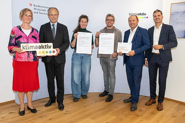 eine Gruppe von Menschen auf einer Bühne hält Urkunden in die Kamera