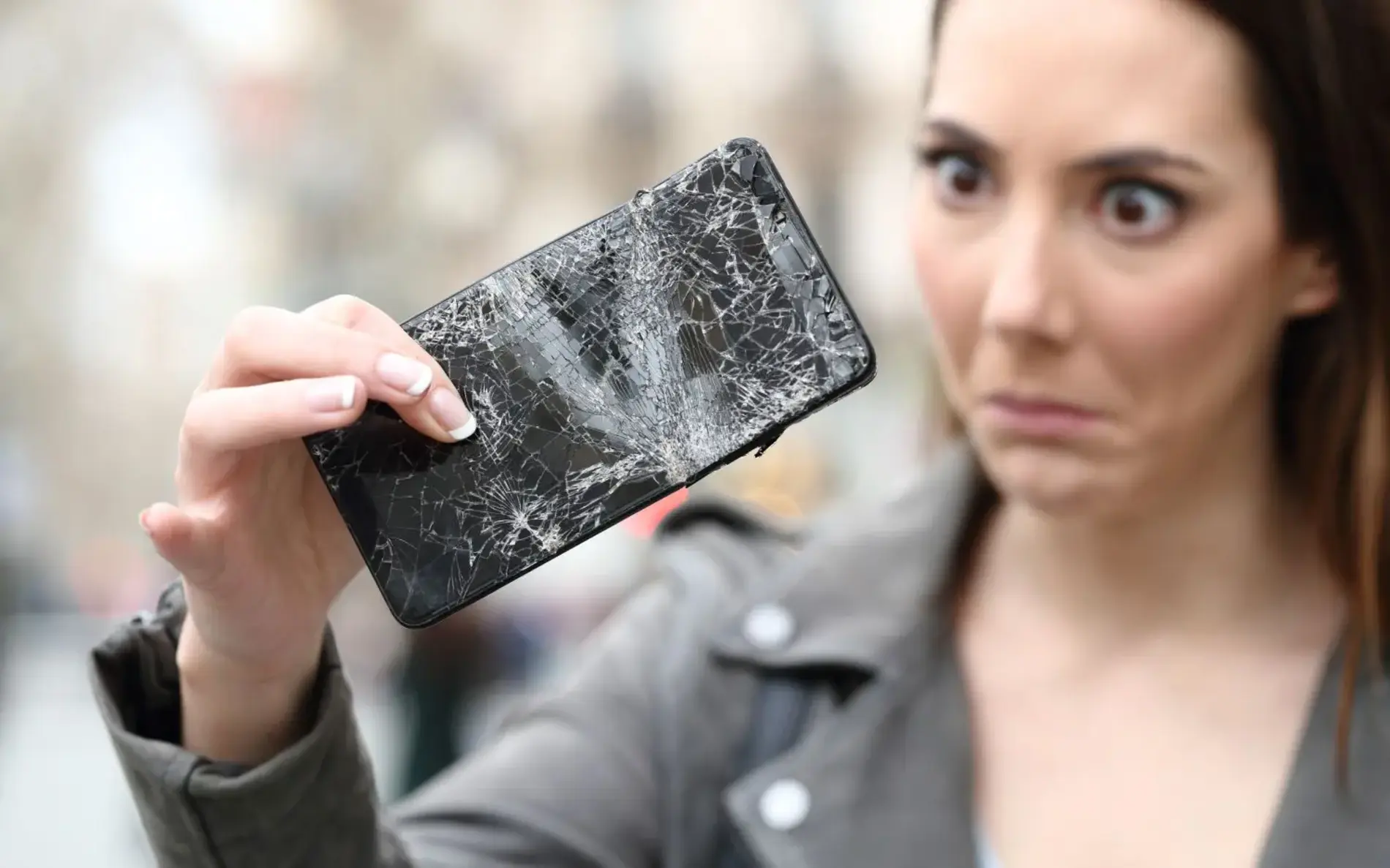 Frau hält Handy mit kaputtem Display in der Hand