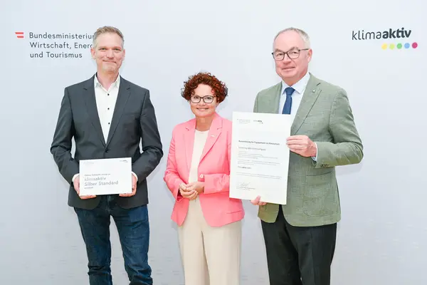 Personen mit Urkunde schauen in die Kamera