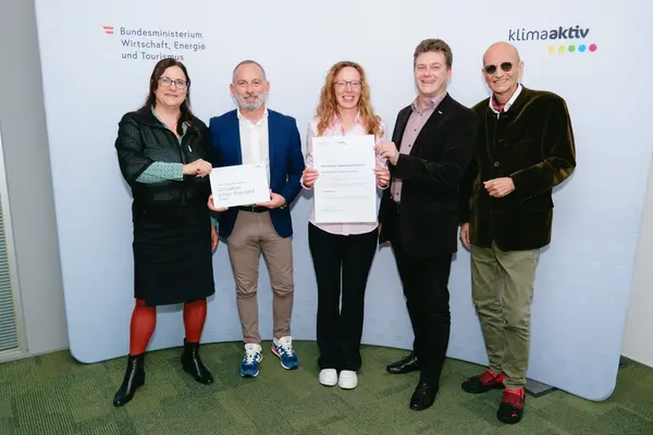 Personen mit Urkunden schauen in die Kamera