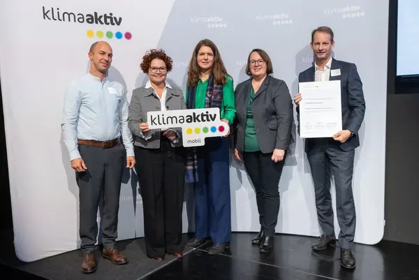 5 Personen mit Urkunde und klimaaktiv Schild schauen in die Kamera