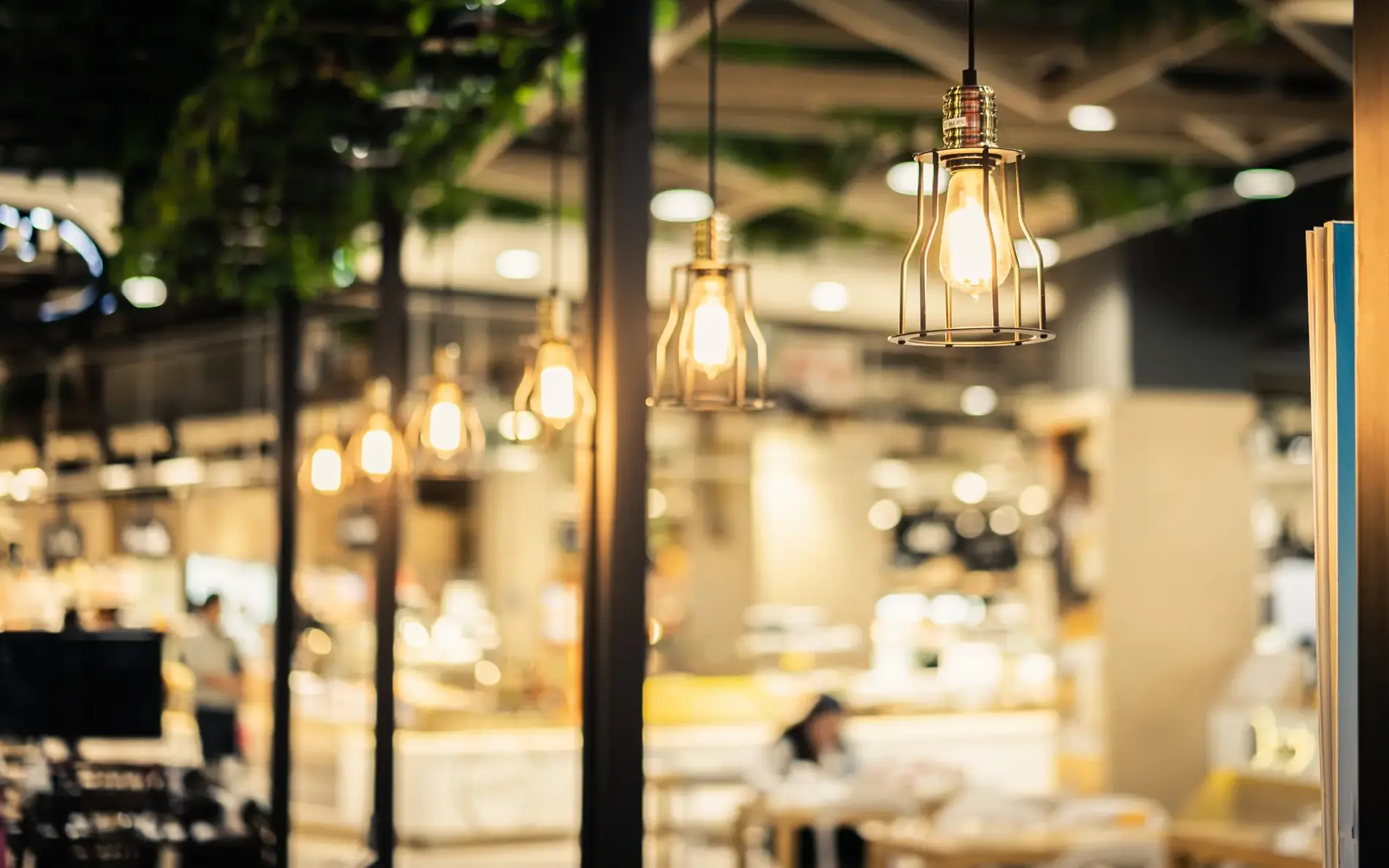 Stilvolle Hängelampen leuchten in einem Restaurantbereich mit warmem Licht und gemütlicher Atmosphäre.