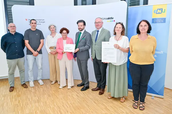 Personen mit Urkunde schauen in die Kamera