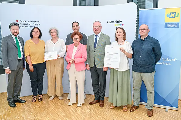 Personen mit Urkunde schauen in die Kamera