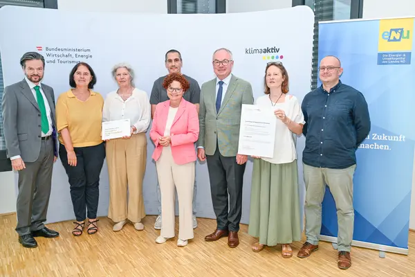 Personen mit Urkunde schauen in die Kamera