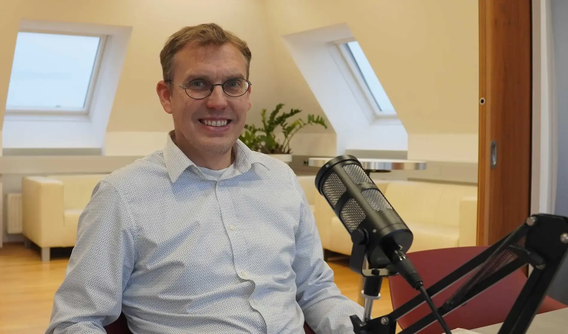 Fritz Hudribusch sitzt im Besprechungsraum der AEA vor dem Podcastmikrofon.