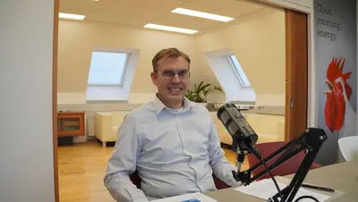 Fritz Hudribusch sitzt im Besprechungsraum der AEA vor dem Podcastmikrofon.