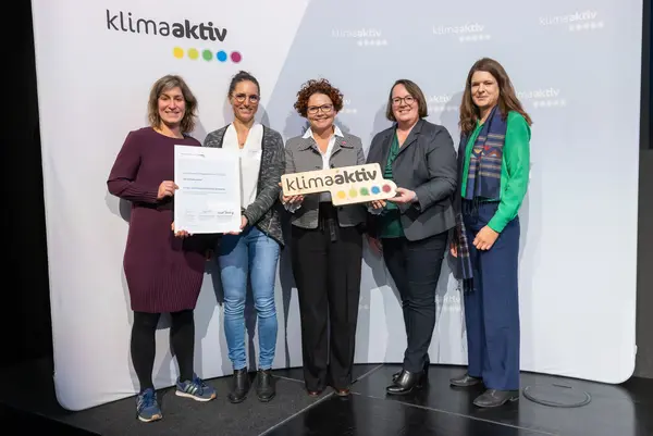 5 Personen mit Urkunde und klimaaktiv Schild schauen in die Kamera