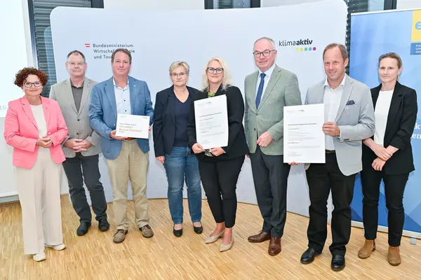 Personen mit Urkunde schauen in die Kamera