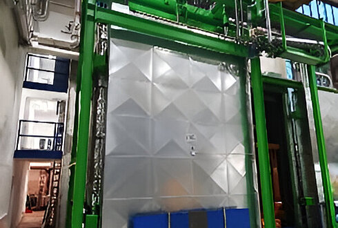 Großer Wicklungsofen mit grünem Rahmen und geschlossener Metalltür in einer Produktionshalle.