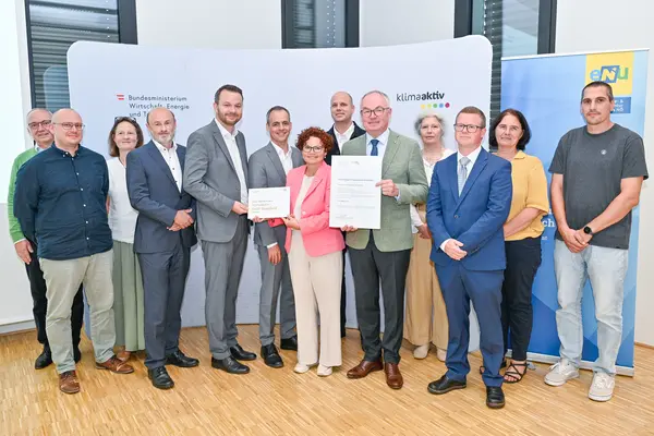 Personen mit Urkunde schauen in die Kamera