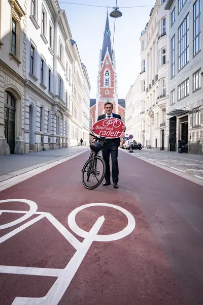 Ein Radfahrer posiert auf der neu umgestalteten Argentinierstraße, welche jetzt eine Fahrradstraße ist mit rotem Untergrund und einer großen Rad-Bodenmarkierung. Im Hintergrund die Elisabethkirche.
