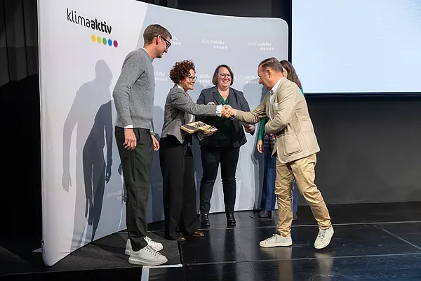 Personen auf einer Bühne gratulieren sich, schütteln Hände