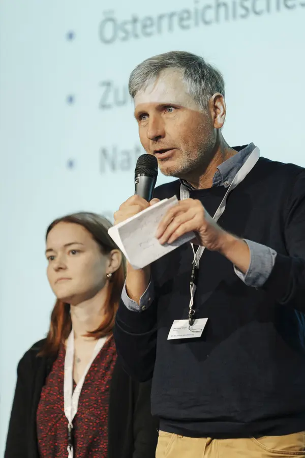 Mann mit Mikro am Podium