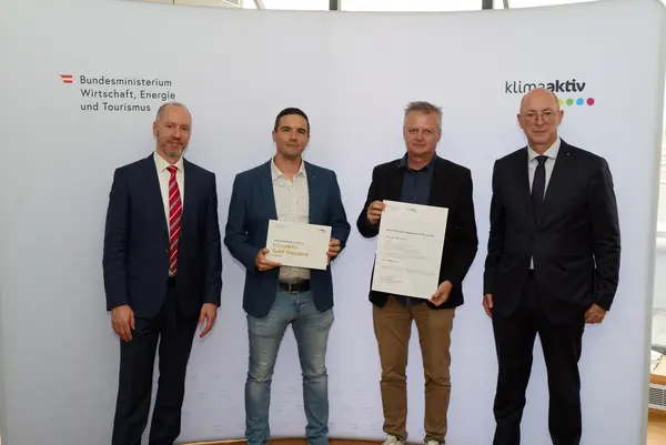 4 Personen mit Urkunde schauen in die Kamera