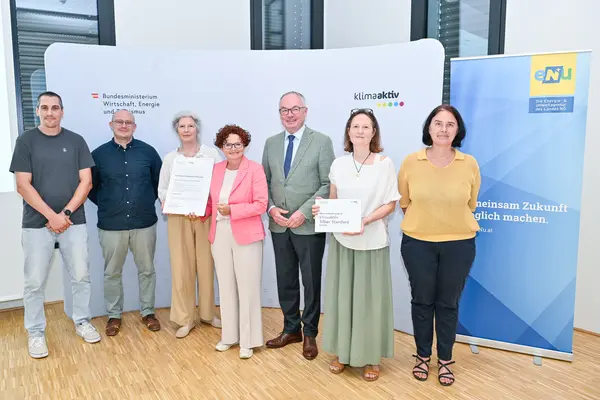 Personen mit Urkunde schauen in die Kamera