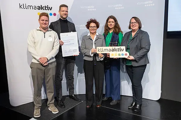 5 Personen mit Urkunde und klimaaktiv Schild schauen in die Kamera
