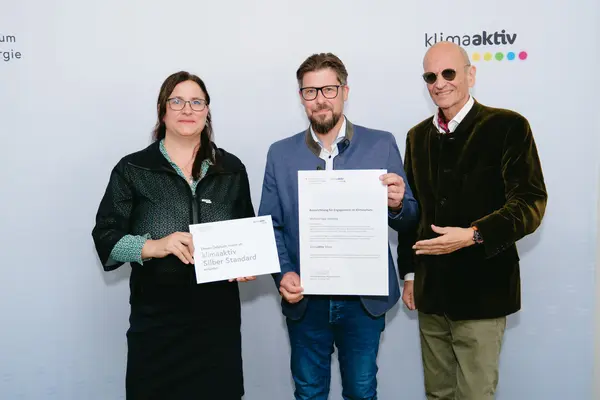 Wohnanlage Almweg Personen mit Urkunden schauen in die Kamera