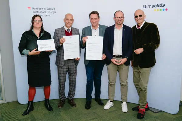 Personen mit Urkunden schauen in die Kamera