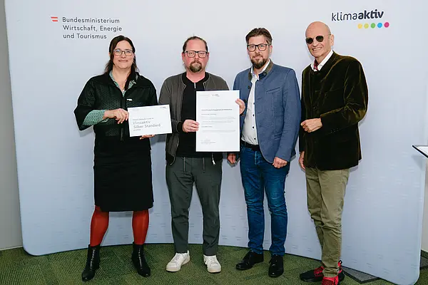 Personen mit Urkunden schauen in die Kamera