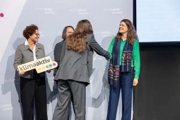 Personen auf einer Bühne gratulieren sich, schütteln Hände