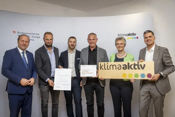 Menschen mit Urkunde schauen in eine Kamera